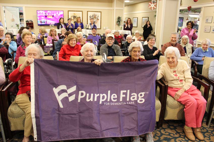 Memory care residents holding the Purple Flag for Dementia Care.